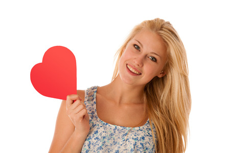 31478611 - beautiful young blonde woman with blue eyes holding red hart banner for valentines day isolated over white