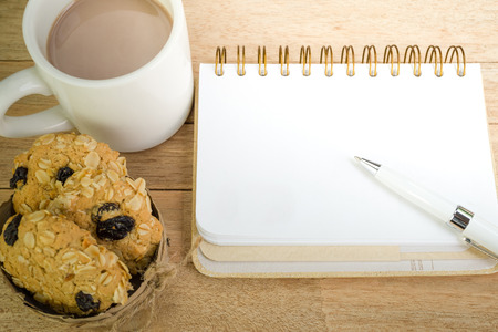 53649616 - blank notebook with coffee and oat cookies on wood background